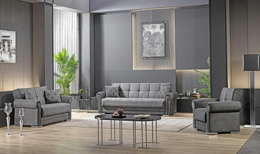 Ein modernes Wohnzimmer mit grauen Wänden verfügt über ein graues Sofa, zwei 8502 Rosi Sessel und einen runden schwarzen Couchtisch. Zur zeitgenössischen Einrichtung gehören Wandkunst, Topfpflanzen und eine Stehlampe von Möbelhaus. Der Raum hat einen hellen Holzboden und elegante Designelemente.